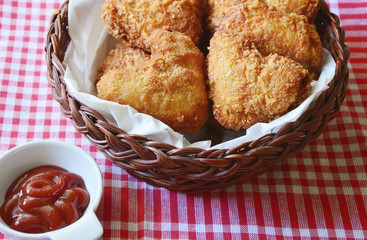 Fried chicken wings are heart-shaped in a basket with ketchup