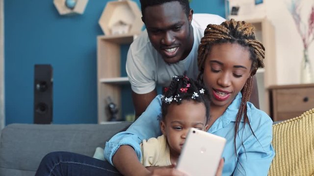 Happy young family taking selfie, brightly smiling straight to phone&rsquo;s camera. Family portrait, childhood memories. Close up view, camera stabilizer shot