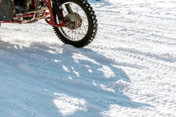 Motorcycle racing in the snow.Heavy red  motorcycle on a white snowy road. A fragment of a close-up.
