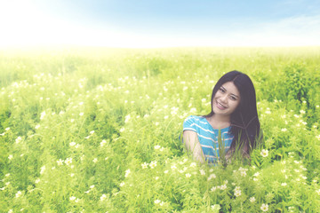 Fototapeta premium Beautiful woman sitting on the blossom meadow