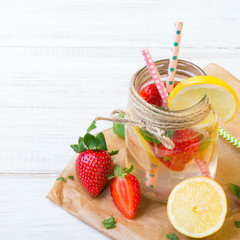 Mineral  water with fresh strawberries, lemon  and mint in jar on a white wooden background, copy space