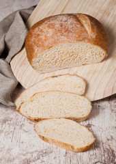 Freshly baked bread loaf with pieces on wood board