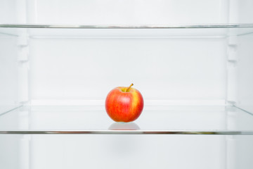Beautiful, fresh, colorful apple on fridge shelf in the kitchen. Healthy sweet food concept. New start for healthy nutrition, body slimming, weight loss. Cares about body.
