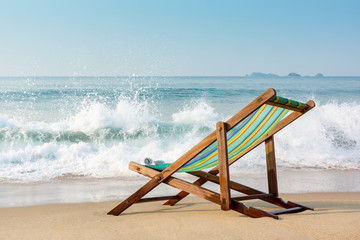 Fototapeta na wymiar Single beach chair or folding chair on the beach with many bubbles of Sea wave, Vacation and holiday concept