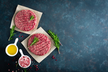 Fresh minced beef meat burgers with spices on dark background. Raw ground beef meat. Flat lay. Top...