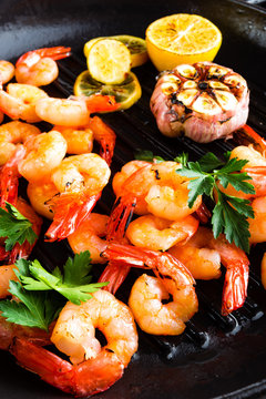 Prawns roasted on grill frying pan with lemon and garlic. Grilled shrimps, prawns. Seafood. Closeup. Dark background