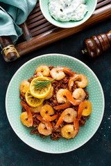 Prawns roasted on grill and boiled brown rice on plate. Grilled shrimps, prawns with rice. Seafood. Asian cuisine. Top view. Dark background