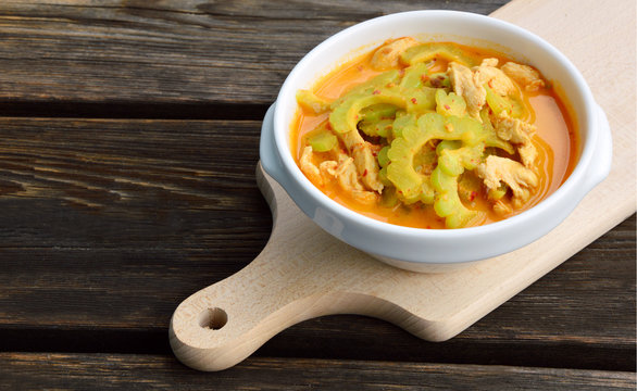 Thai Chicken Curry with Bitter Gourd in white bowl on wooden background