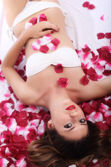 Naklejka na ściany i meble Beautiful girl in petals of roses