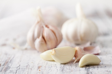 Peeled cloves of garlic and a head of garlic on old wooden table