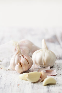 Peeled cloves of garlic and a head of garlic on old wooden table