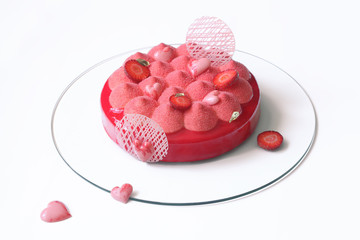 Contemporary Strawberry Mousse Cake covered with red velvet spray and red mirror glaze, on white...