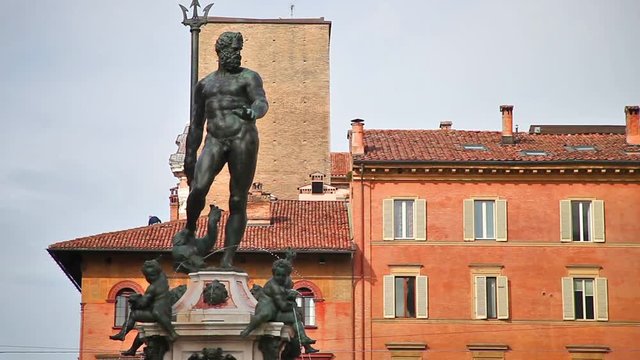 Architecture panorama of Bologna city in Emilia region of Italy. Neptune bronze statue and restored fountain, with historic orange-red buildings background in Nettuno square of the town center.