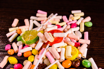 Different multi colored candies on a dark wooden table