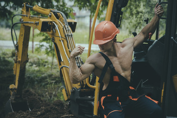 Sexy man with nude torso near construction equipment