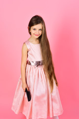 Girl child brush hair in fashionable dress on pink.