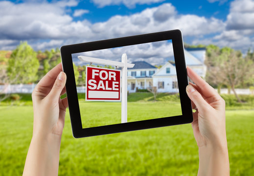 Female Hands Holding Computer Tablet with Home For Sale Sign on Screen, House Behind.