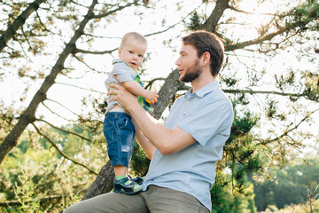 Father having fun with his little son outdoors. man with a beard playing with kid in park