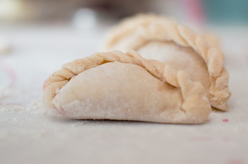 Homemade potstickers with flour laying on the modern cooking surface.