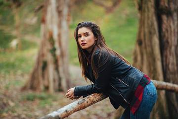 Portrait of a beautiful young woman in a leather jacket in the park