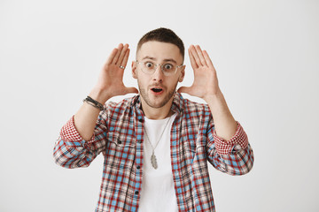 My brain explodes from this gossips. Studio shot of shocked and excited handsome man in trendy...