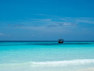 Blue ocean with wooden fish boat on horizon. Zanzibar Island, Tanzania, Africa, February 2018.
