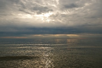 Sunset sky over sea. Sun rays between clouds and beauty reflections on the water.