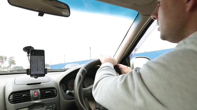 driver rides in the car and uses the GPS navigator in the smartphone.