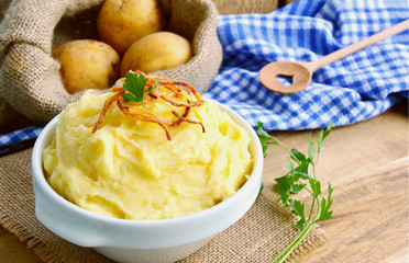Mashed potatoes or Puree in white bowl with Crisp onion and parsley on wooden background