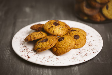 Chocolate cookies placed on a plate on a dark background.