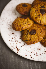 Chocolate cookies placed on a plate on a dark background.
