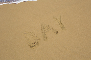 Day written in the sand on sea background