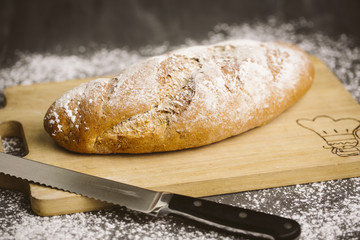Fresh breads on dark wood with sprinkled flour.