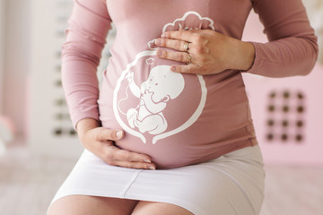 hands of women tenderly embrace a pregnant tummy