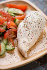 Close-up of boiled chicken breast fillet with fresh vegetables on a bamboo tray, selective focus, vertical shot