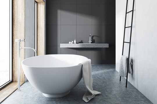 Gray bathroom, white tub, ladder, concrete floor