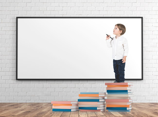 Little boy with a marker on books pile whiteboard