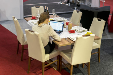 A girl at a dinner table working on a laptop