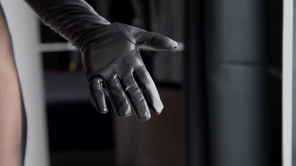 Female hit her hand in leather black glove with stack. Woman spank her hand palm with crop whip.