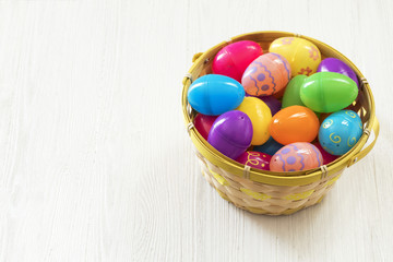 Fototapeta na wymiar Easter eggs in basket on white wooden background