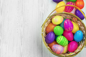 Easter eggs in basket on white wooden background