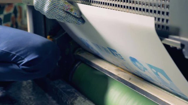 An employee is putting typography template into a rolling machine.