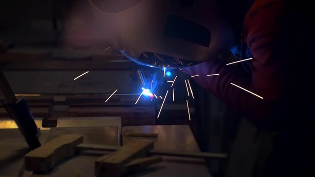 man in a shirt shirt and wearing a protective mask conducts welding work.