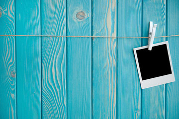 Полароидный снимок, висящий на джутовой веревке с прищепкой на голубом деревянном фоне