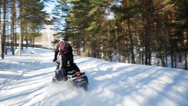 Father with little daughter riding on a snowmobFather and daughter snowmobiles in the forestile