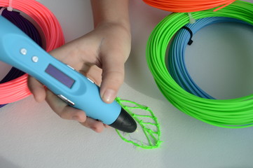 Child draws a 3D pen. The hands of the kid hold the 3D blue pen with plastic