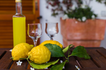 Lemonade or limoncello in a glass bottle, glasses, lemons with leaves on a serving table on the...