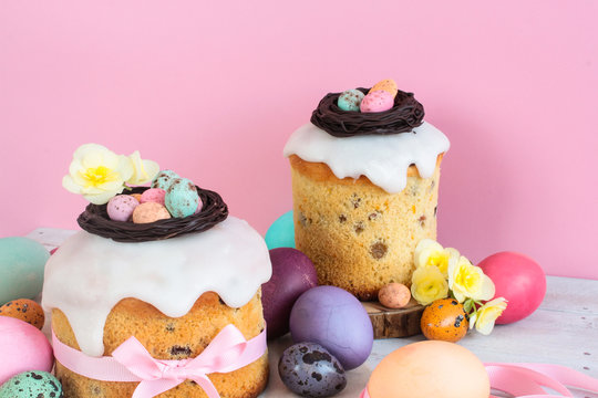 Colorful Easter spring stillife in soft light and trendy pastel colors. Traditional cake with chocolate nest, candy and qail eggs decoration blossom flowers on pink background