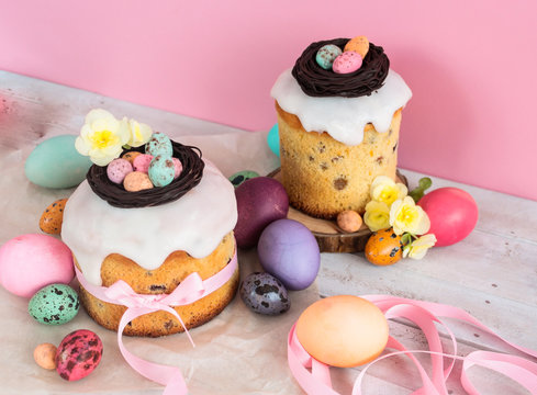 Colorful Easter spring stillife in soft light and trendy pastel colors. Traditional cake with chocolate nest, candy and qail eggs decoration blossom flowers on pink background