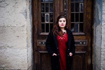 Brunette plus size model at red on street of city.